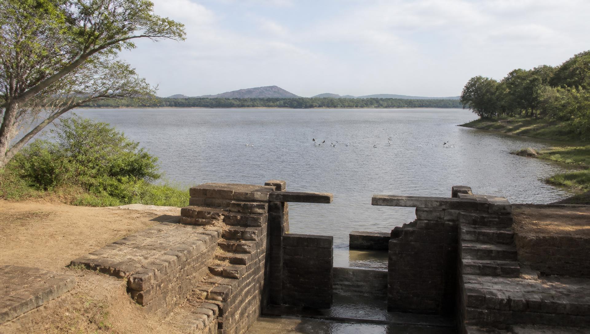 The ancient stone sluice and open water of Sorabora Wewa