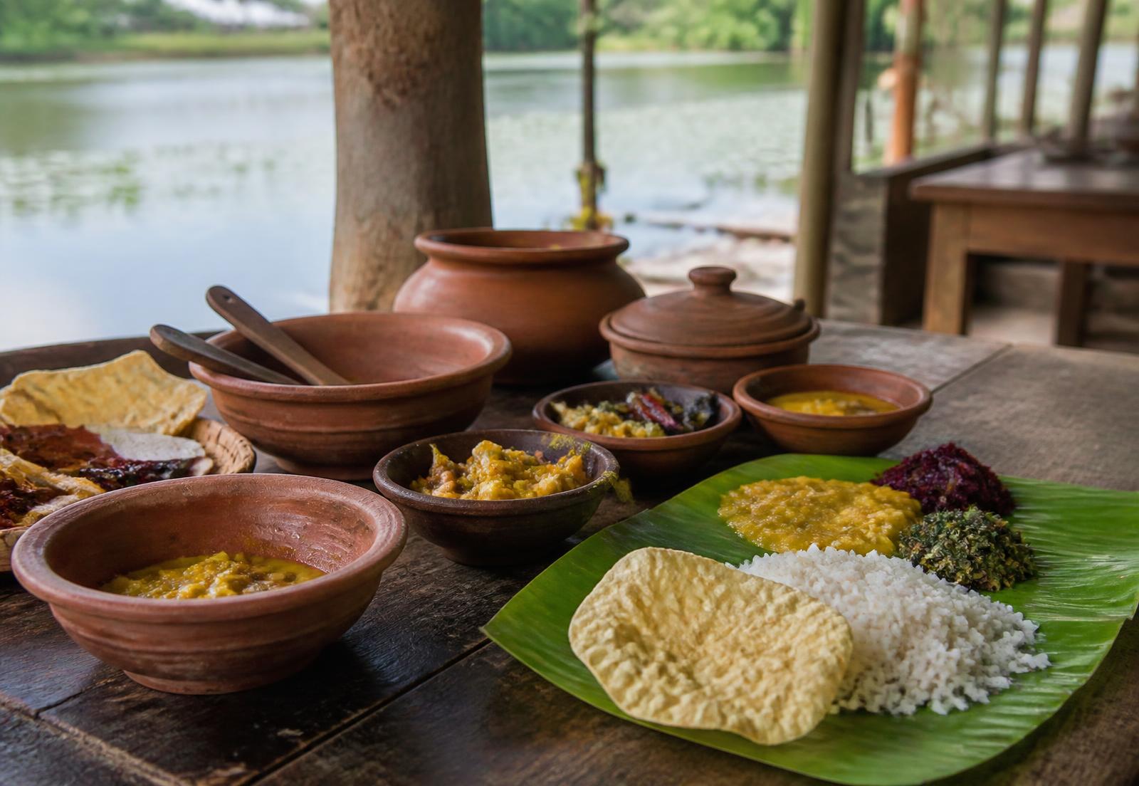 Traditional Sri Lankan village meal served in clay pots beside Sorabora Wewa